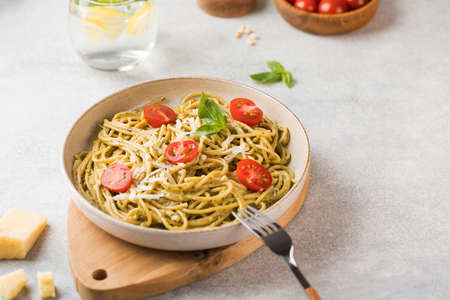 Spaghetti pasta with pesto sauce, parmesan cheese and cherry tomatoes on a plate. Menu, Italian cuisine. Copy space.の写真素材