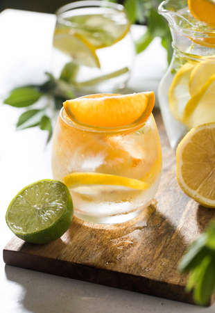 Refreshing lemonade with lemon and mint in a jug and glass on a wooden board. Summer drinks. Copy...
