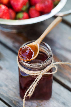 Strawberry jam in a jar on a wooden board. Fermented berries.の写真素材
