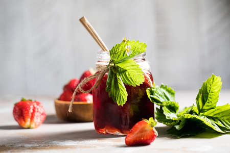 Strawberry jam in a jar on a wooden board. Fermented berries.