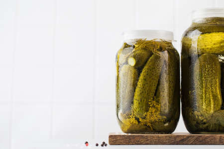 Pickled cucumbers in jars on a white background. Canning vegetables. Copy space.の写真素材