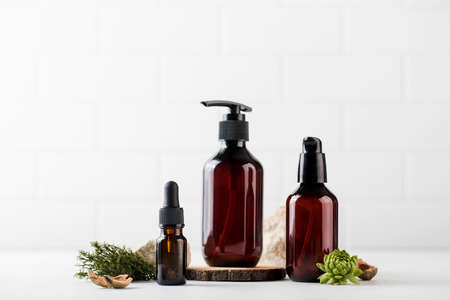 Three different brown glass bottles with eco-friendly organic cosmetic products surrounded by natural materials.の写真素材