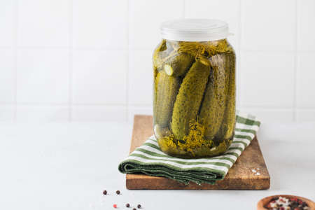 Pickled cucumbers in jars on a white background. Canning vegetables. Copy space.