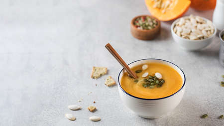 Pumpkin cream soup in a bowl with seeds on a gray background. Comfortable riding, autumn menu. Copy space,の写真素材