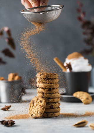 Woman pours cinnamon onto cookies with chocolate on table