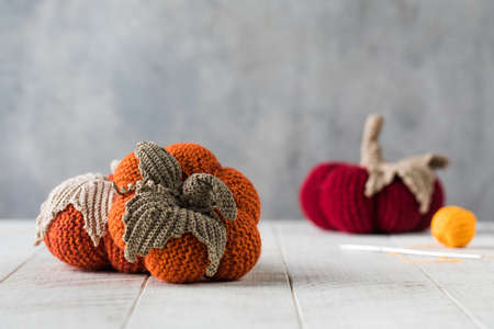 Handmade knitted pumpkins with leaves on white tableの写真素材