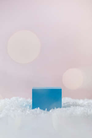Blue cube in snow on pink background with festive lightsの写真素材
