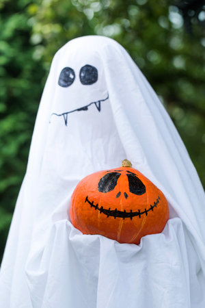 Ghost holds pumpkin with spooky face in green backyard