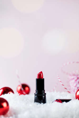 Red lipstick tube and Christmas tree baubles on artificial snow pileの写真素材