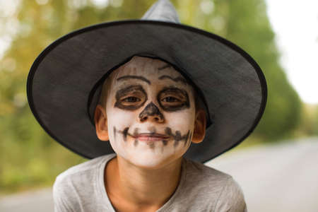 Smiling kid with skeleton makeup and witch hat in parkの写真素材