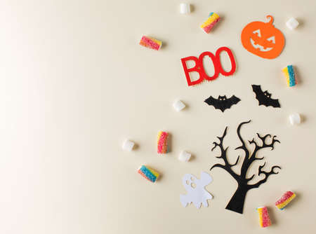 Halloween composition with scattered candies and holiday symbols on beige colorの写真素材