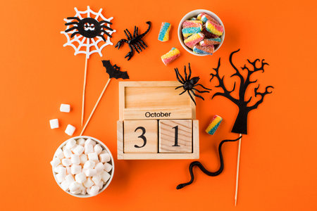 Halloween composition with block calendar sweet treats spooky decor on orangeの写真素材