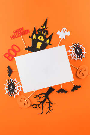 Halloween greeting card with funny holiday symbols and blank paper on orangeの写真素材