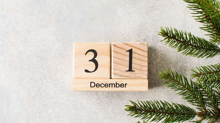Wooden bars show date of New Year eve on white background with Christmas tree branchの写真素材