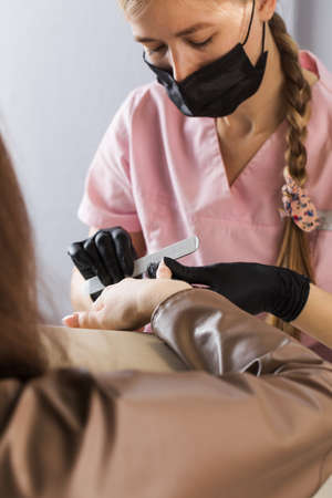 A manicurist files nails with a metal file. Manicure process in a beauty salon.の写真素材