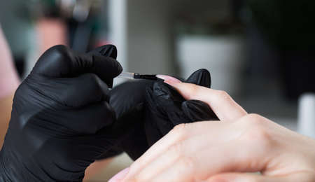 Manicure process in a beauty salon. The manicurist paints the nail with varnish.