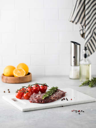 A piece of fresh raw beef steak on a board with rosamarin and cherry podimors.の写真素材