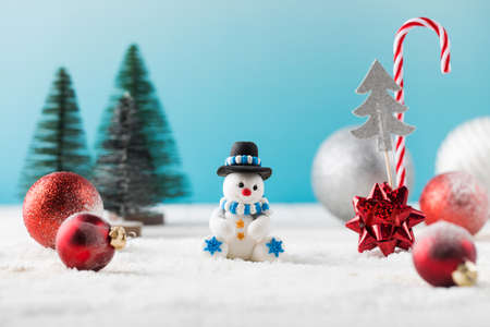 Snowman in hat and red baubles with traditional Christmas ornate on fake snowの写真素材
