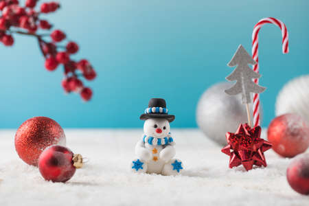 Snowman in hat and red baubles with traditional Christmas ornate on fake snowの写真素材