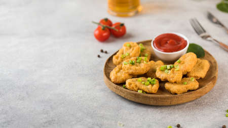 Golden chicken nuggets in wooden plate, sprinkled with green onions and a lemon wedge. Pub menu. Copy spaceの写真素材