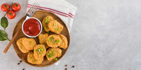 Golden chicken nuggets in a wooden plate, sprinkled with green onions and a lemon wedge. Copy space. Flatlayの写真素材