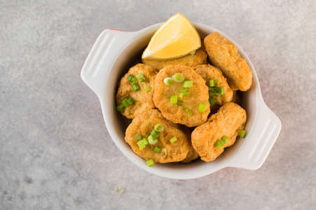 Golden chicken nuggets in a plate, sprinkled with green onions and a lemon wedge. Copy space. Flatlayの写真素材