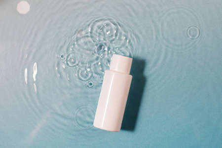 Bottle of cosmetic product with space for text on blue surface with clear waterの写真素材