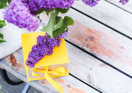Gift box with yellow ribbon and lilac bouquets. A greeting card.の写真素材