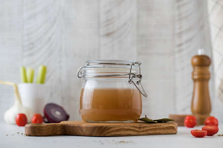 Bone broth soup in glass jar for storage on a wooden board. The concept of healthy eating.の写真素材