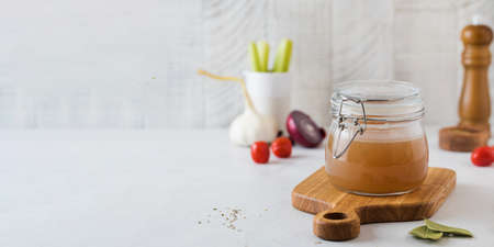 Bone broth soup in glass jar for storage on a wooden board. The concept of healthy eating. Copy space.の写真素材