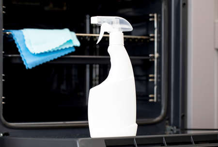 On the door of an open oven is a mock-up of a white spray bottle with oven detergent. General...