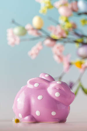 Lilac bunny on a blue background with a branch of flowers. Easter concept.の写真素材