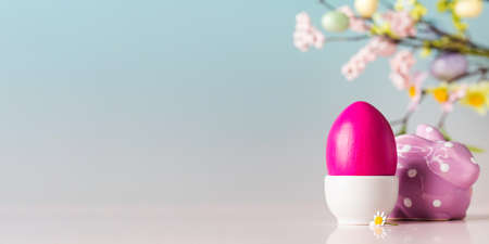 Easter card with a painted egg and a decorative figure of a hare on a blue background with flowers....