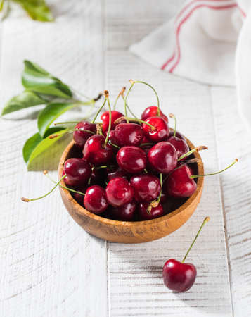 Juicy cherry berries in a wooden bowl on a wooden background.の写真素材
