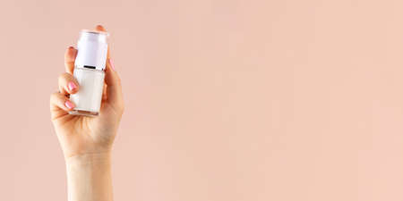 A mock-up of a jar of moisturizer in a womans hand on a pink background. Copy space.