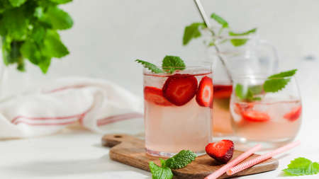 Homemade refreshing strawberry lemonade in glasses and jug with fresh strawberries and mint leaves. Summer drinkの写真素材