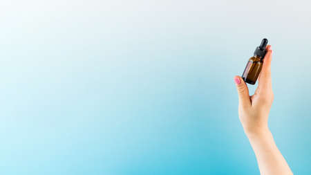 A mock-up of a brown dropper with skin oil in a womans hand. Copy space.の写真素材