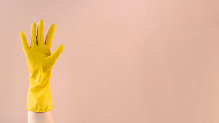 Hand in yellow rubber glove shows OK gesture with fingers on beige background. Copy spaceの写真素材