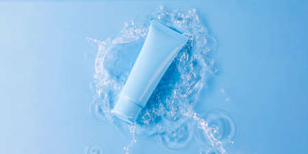 Blank tube of skincare product and splashing water on blue background upper viewの写真素材