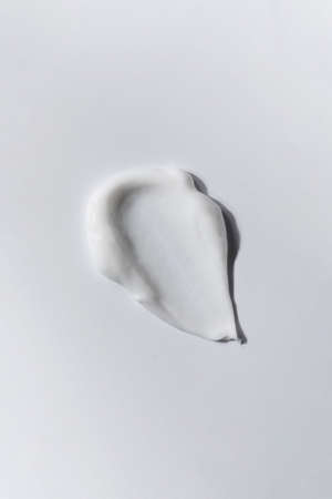 A smear of white skin cream on a white background. Cosmetic texture.の写真素材