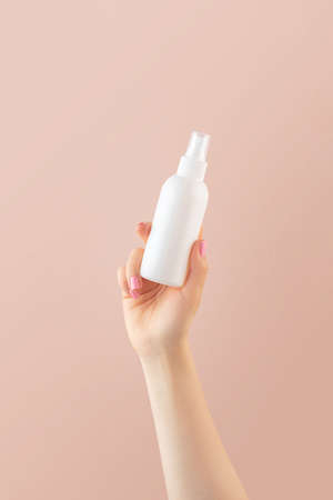 Lady hand sprays air refresher from blank bottle on pink background close viewの写真素材