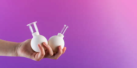 Woman holds pumps for lymphatic drainage massage on purple background closeupの写真素材