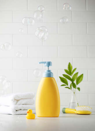 Yellow bottle of children cosmetic product and toy rubber duck in bathroomの写真素材