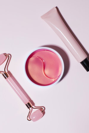 A jar with eye patches with collagen and retinol, a tube of cosmetics and a quartz roller for facial massage.の写真素材