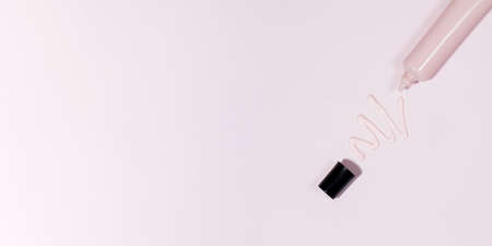 A pink tube with cosmetics and a squeezed creamy cosmetic product. Face cream, foundation. Copy spaceの写真素材
