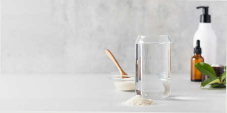 A glass of water, a slide of collagen powder, care cosmetics. Anti-aging procedures, nutritional supplements for healthyの写真素材