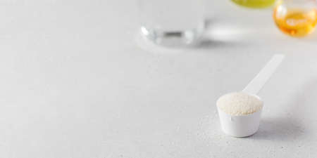 A scoop with hydrolyzed collagen powder against the background of laboratory flasks. Food additives, healthy.の写真素材