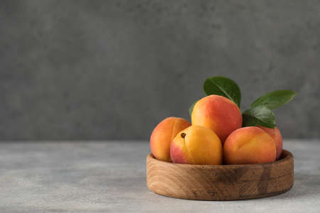 Ripe juicy apricots on a wooden plate on a gray background. Copy spaceの写真素材