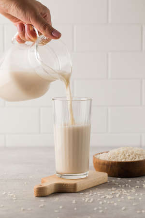 Vegetable rice milk is poured from a jug into a glass. Alternative milk.の写真素材