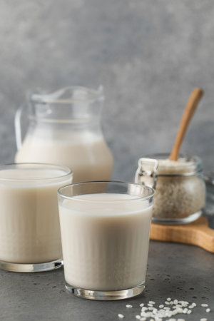 Glasses of vegetable rice milk and a jug on a gray background. Vegetarian food, lactose free milk.の写真素材
